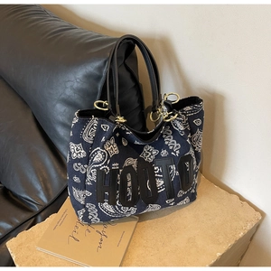 Detail of blue paisley canvas tote bag with black HOOTO logo on a stone base