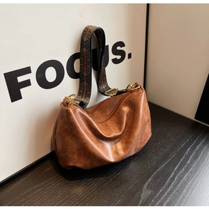 Close-up of brown pleated hobo bag with a wide ethnic style jacquard shoulder strap