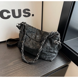 Detail of black quilted leather texture and silver chain strap on vintage shoulder bag