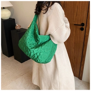Green quilted bucket bag detail with textured floral pattern and satin finish