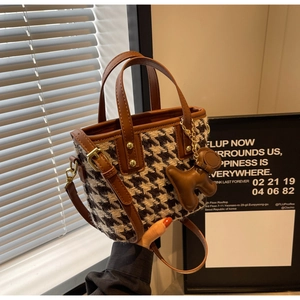Detail van mini tote bag met houndstooth patroon, bruine lederen handvaten en hondenbedel