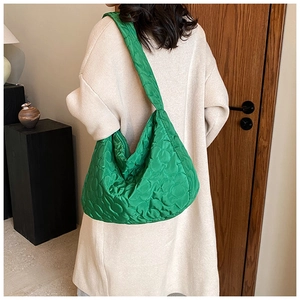Model wearing a bright green quilted hobo bag with 3D floral patterns in a home setting
