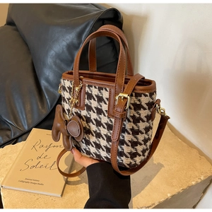 Detail van de pied-de-poule crossbodytas met leren handvat en schattige berenhanger