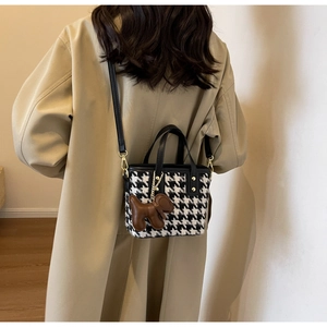 Detail van de mini-tas van pied-de-poule tweed met schattige bruine pluche puppy-hanger