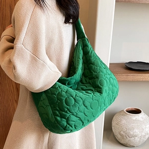 Quilted grass green nylon bucket bag with large floral stitching and wide shoulder strap