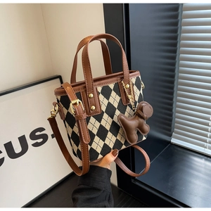 Detail van gebreide crossbodytas met bruine bies en schattige puppy-bedel aan het handvat