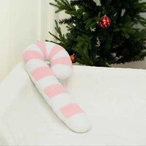 Cuscino di peluche a bastoncino di zucchero rosa e bianco su divano con albero di Natale
