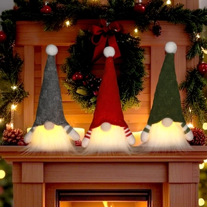 Three LED lighted Christmas gnomes with knitted hats and long beards on a fireplace mantel