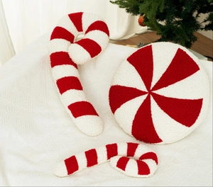 Detailed view of red and white striped plush candy pillows on a beige sofa