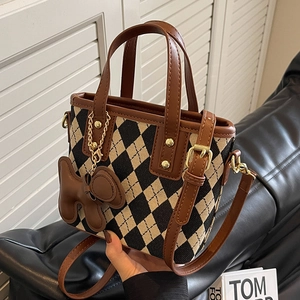 Chique beige en zwarte gewatteerde bucket bag met lederen handvatten en hanger