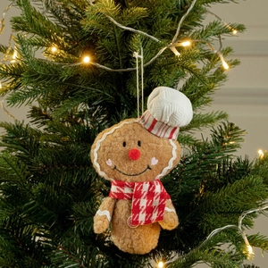 Gingerbread man plush ornament with chef hat and scarf hanging on a Christmas tree