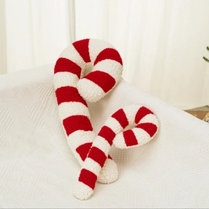 Pair of red and white striped candy cane plush pillows on a cozy white sofa surface