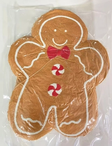Detailed view of gingerbread man plush pillow with red bow tie and candy buttons