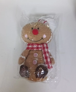 Detail of gingerbread man plush with red checkered scarf and white chef hat in packaging