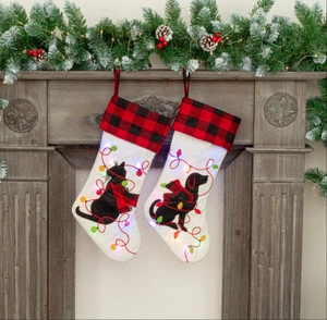 Close-up of LED glowing Christmas stockings with cat and dog embroidery on fireplace