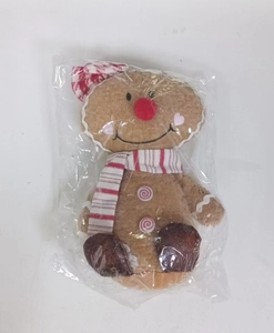 Macro shot of gingerbread man plush with red striped scarf and pink button details