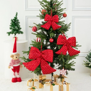 Close-up of red velvet Christmas bows with gold patterns hanging on a decorated tree
