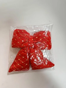 Detail of red velvet Christmas bow with gold grid patterns and sequins in clear packaging