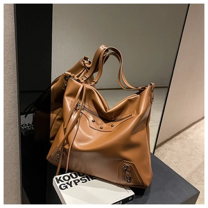 Detail of caramel brown large tote bag featuring moto-style zippers and stud accents