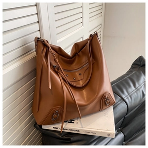 Detailed view of caramel leather tote with vintage rivets and long fringe tassels