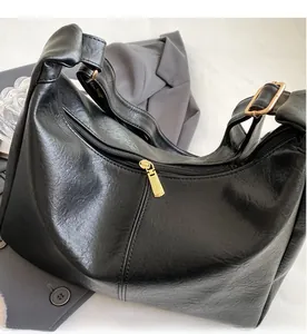 Close-up of high-quality smooth gold zipper and wrinkled leather texture on black tote bag