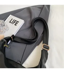 Detail of adjustable black leather shoulder strap with gold metal buckle on tote bag