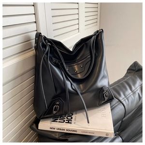 Detail of black leather tote bag featuring silver studs and long fringe tassels