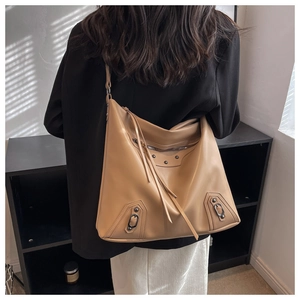 Detail of camel PU leather tote featuring decorative tassels and dark metal studs