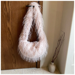 Détail du sac à épaule en peluche rose clair avec fausse fourrure suspendu à une porte
