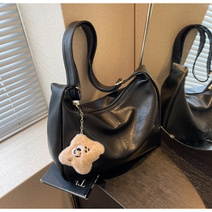 Detail of black faux leather crescent hobo bag with star plush charm and metal zipper