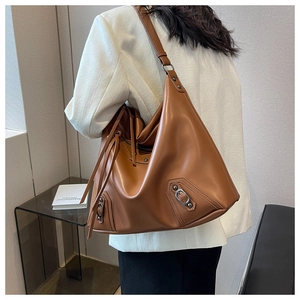 Brown leather large tote bag featuring moto-style metal buckles and rivets on model