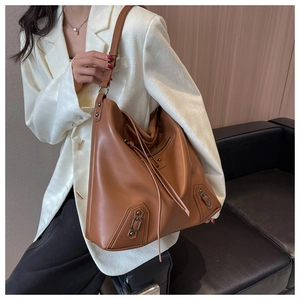 Close-up of brown tote bag featuring retro metal buckles and long fringe tassel detail