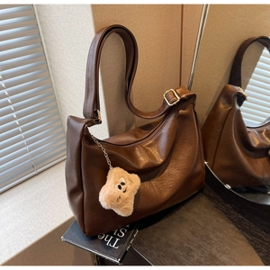 Macro view of textured brown PU leather hobo bag with gold buckle and star pendant