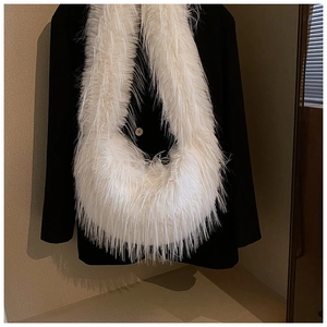 Gros plan du sac bandoulière en fausse fourrure blanche sur un costume noir élégant