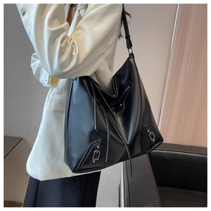 Detail of black motorcycle tote bag showing silver metal buckles and long fringe tassels