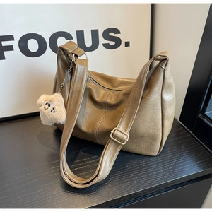 Detailed texture of dark khaki faux leather bag with cute plush puppy charm