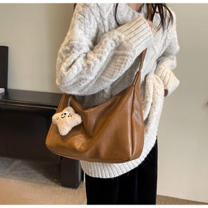 Brown retro shoulder bag with a plush star charm worn by a model in a warm room