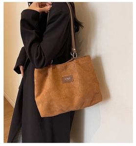 Close-up of brown corduroy tote bag featuring heart patterns and leather logo detail