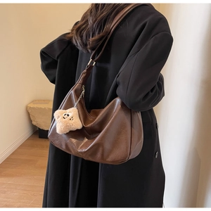 Detail of a large brown hobo bag with glossy oil leather texture and star plush charm