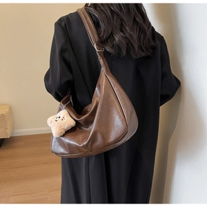 Detailed shot of brown faux leather hobo bag with plush star charm and metal buckle strap