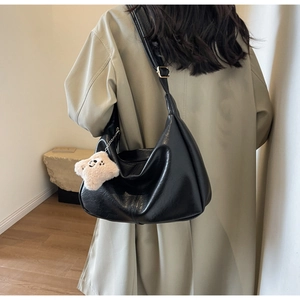 Detail of black glossy PU leather hobo bag texture with cute plush biscuit charm