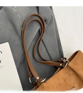Detail of a brown tote bag showing a faux leather shoulder strap with silver ring buckle