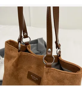 Detail view of brown corduroy tote bag with heart embossed pattern and leather straps