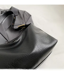 Détail de la texture cuir noir sur un grand sac hobo avec une boucle en métal doré