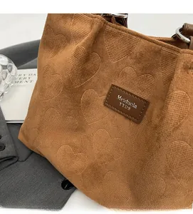 Close-up of brown tote bag featuring heart pattern embossing and leather logo detail
