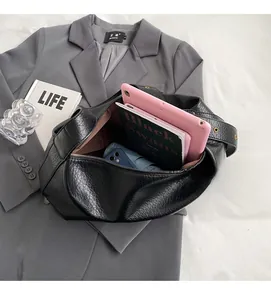 Détail intérieur du sac bandoulière noir grainé contenant une tablette et des livres
