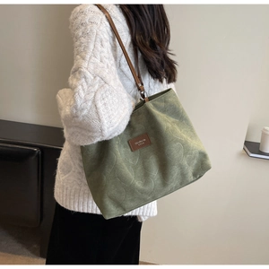 Detail of avocado green tote bag featuring 3D heart embossing and leather logo plate