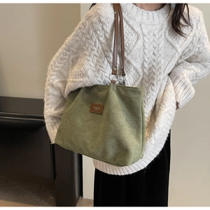 Detail of green velvet tote with heart embossing and brown leather strap handles