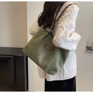 Detail view of vintage green tote bag with heart-embossed texture and brown shoulder strap