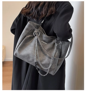Detail of grey vintage textured tote bag with silver chains and metallic branding